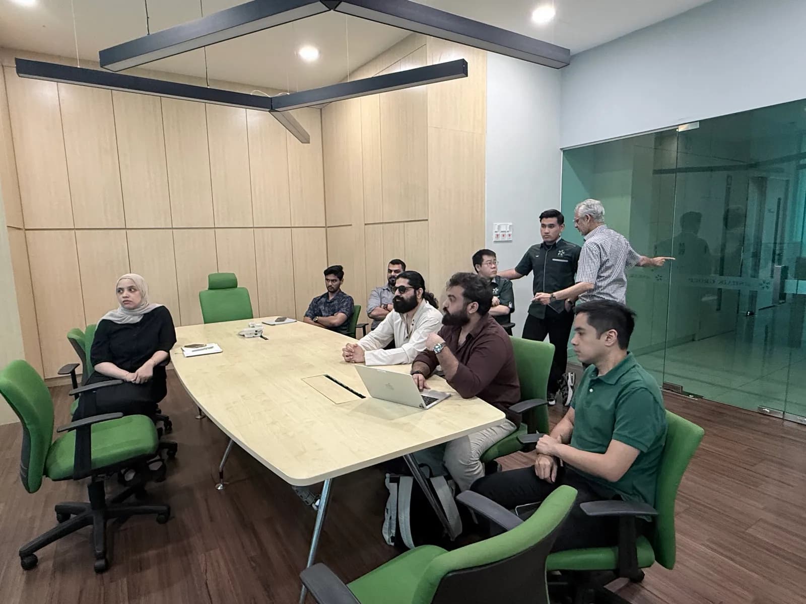 Members of the Watson and Poliklinik Shaik teams around a meeting table, one pointing across the room while the others listen.
