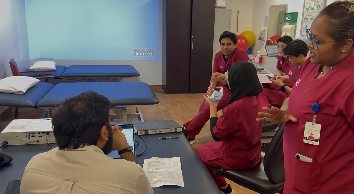 Therapists from Subang Jaya Medical Centre's Rehabilitative Services with a member of the Watson team in the department's treatment room, a printed referral letter on the table between them.